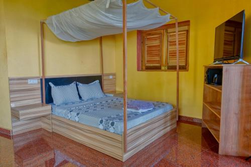 a bed with a canopy in a room at Colibri Lodge in Ambatoloaka