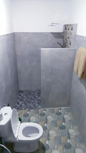 a bathroom with a toilet and a stone floor at Ella Secret Paradise in Ella