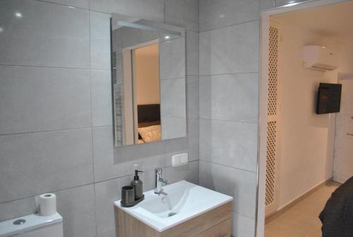Baño blanco con lavabo y espejo en KiCo, en Cómpeta