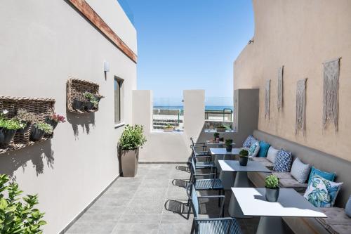 eine Terrasse mit Tischen und Stühlen mit Meerblick im Hintergrund in der Unterkunft Ciel Collection Suites in Chania