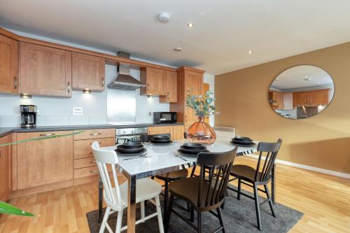 a kitchen with a table with chairs and a mirror at Riverview Apartments in Glasgow