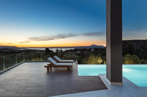 a patio with a lounge chair and a view of the sunset at Eloa Luxury Villa in Chania Town