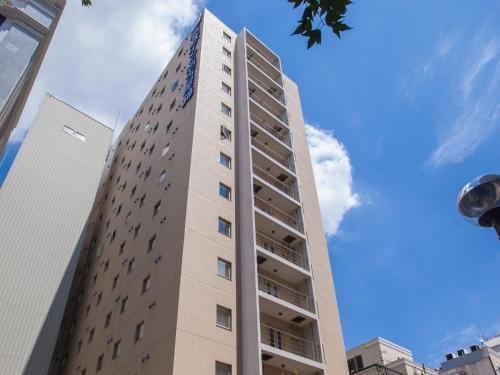 a tall building with a blue sky in the background at Meitetsu Inn Nagoya Nishiki in Nagoya