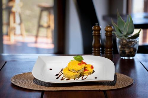 a white plate with food on a wooden table at Kuzuko Lodge in Addo