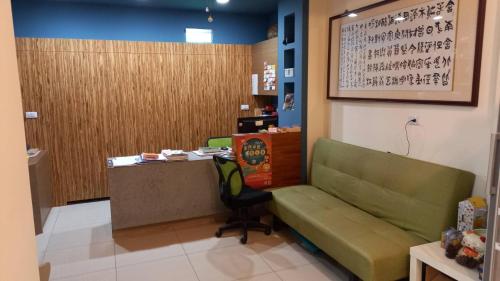 a waiting room with a green couch and a desk at Plum Green Homestay in Jinning