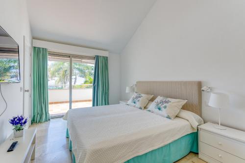 a white bedroom with a bed and a window at BLUE MARLIN 14 in Pasito Blanco