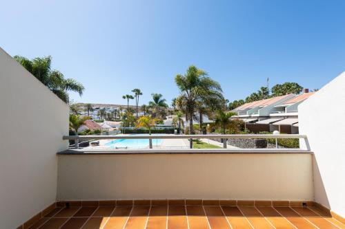 a balcony with a view of a swimming pool and palm trees at BLUE MARLIN 14 in Pasito Blanco