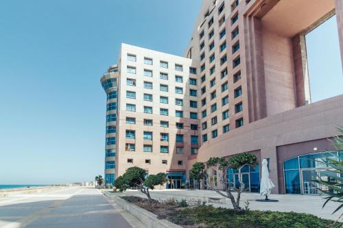 a large building with a beach in front of it at Almog Haifa Israel Apartments מגדלי חוף הכרמל in Haifa