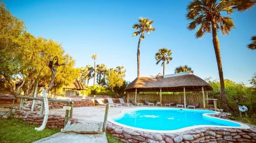 a swimming pool with a gazebo and palm trees at Palmwag Camping2Go in Kamanjab