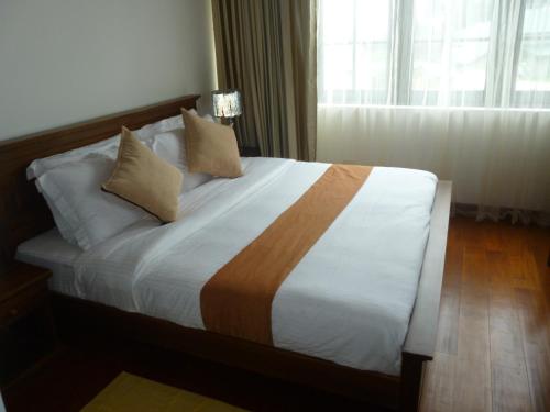 a bedroom with a bed with white sheets and a window at Daffodil's Hotel in Nuwara Eliya