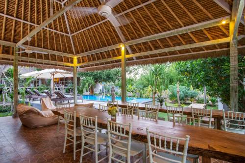 a dining room with a table and chairs and a pool at Komodo Garden in Nusa Lembongan