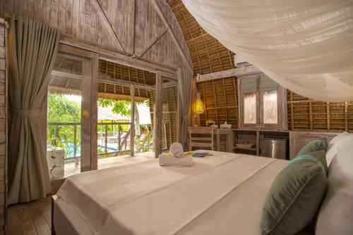 1 dormitorio con 1 cama con dosel blanco en Komodo Garden, en Nusa Lembongan