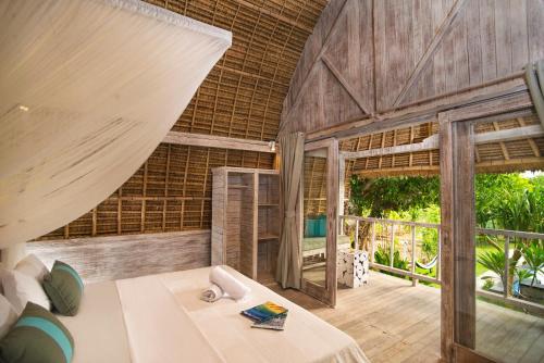 a room with a bed and a large window at Komodo Garden in Nusa Lembongan