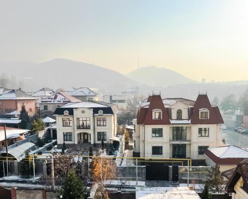 un groupe de maisons dans une ville avec des montagnes en arrière-plan dans l'établissement East Palace Hotel, à Almaty