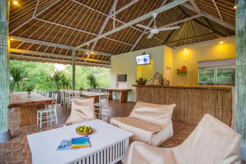 a restaurant with white tables and chairs and a bar at Komodo Garden in Nusa Lembongan