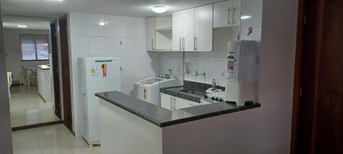 a kitchen with white cabinets and a sink and a refrigerator at Pajuçara Maceio Pé na Areia in Maceió