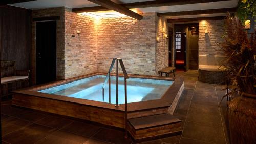 a hot tub in a room with a brick wall at Hotel Kirstine in Næstved