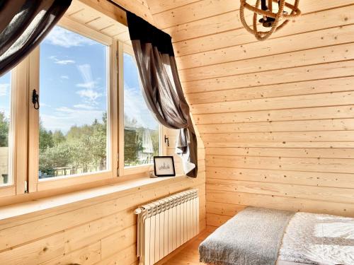 a bedroom with a window in a wooden wall at Osada Frycówka in Nowy Targ