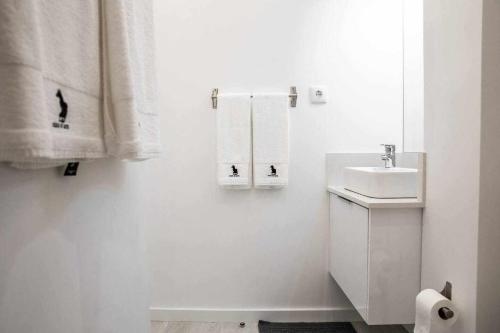 a white bathroom with a sink and towels at Casa do Gato Poeta in Leiria