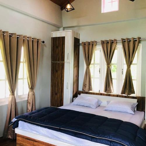 a bedroom with a large bed with windows at Saanidhya Sunset View Villa in Mukteswar
