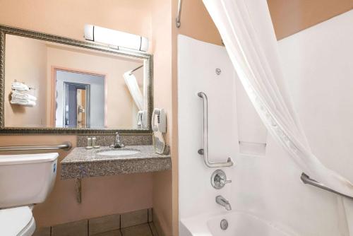 a bathroom with a toilet and a sink and a mirror at Super 8 by Wyndham San Antonio/I-35 North in San Antonio
