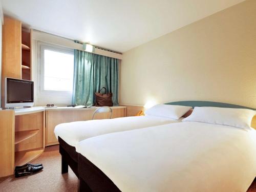 ein Hotelzimmer mit 2 Betten und einem TV in der Unterkunft ibis Koblenz City in Koblenz