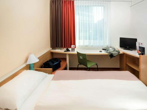 a hotel room with a bed and a desk with a computer at ibis Koblenz City in Koblenz