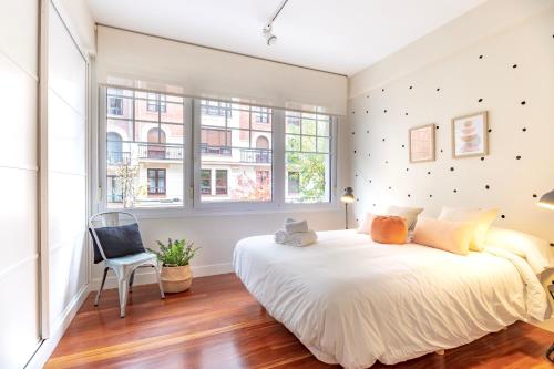 a bedroom with a large white bed and a chair at Gran apartamento CON ESTILO en el CENTRO de Bilbao in Bilbao