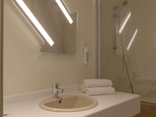 La salle de bains est pourvue d'un lavabo, d'une douche et d'un miroir. dans l'établissement ibis budget Le Puy En Velay, au Puy-en-Velay