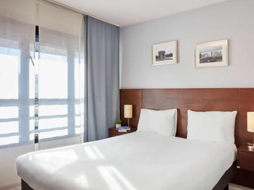 Un dormitorio con una gran cama blanca y una ventana en Aparthotel Adagio Access Paris Bastille, en París