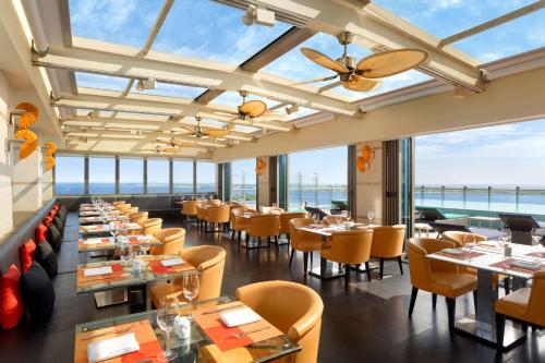 a restaurant with tables and chairs and windows at Jen Maldives Male by Shangri-La in Male City