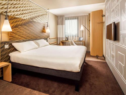 um quarto de hotel com uma cama grande e uma televisão em ibis London Canning Town em Londres