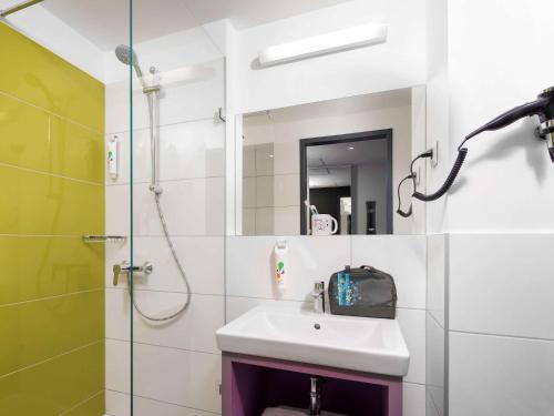 a bathroom with a shower, sink, and mirror at ibis Styles Budapest Airport in Vecsés