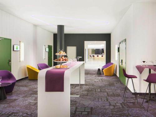 a room with a table with purple and yellow chairs at ibis Styles Budapest Airport in Vecsés