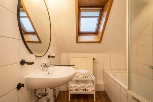 a bathroom with a sink and a mirror and a tub at Ferienwohnung Allgäu in Kißlegg