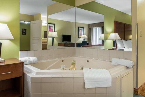 une salle de bain avec une grande baignoire avec un grand miroir dans l'établissement Quality Inn Jacksonville near I-72, à South Jacksonville