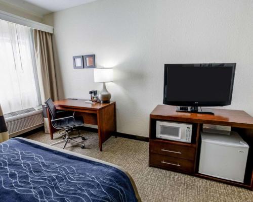 a hotel room with a bed and a desk with a television at Comfort Inn Kearney - Liberty in Kearney
