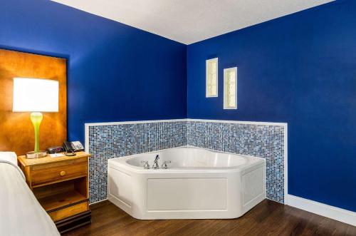 a blue bathroom with a white bath tub next to a bed at Clarion Hotel Seekonk - Providence in Seekonk