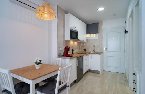 a kitchen with a wooden table and a dining room at Júpiter Suites by Kaarina in Benalmádena