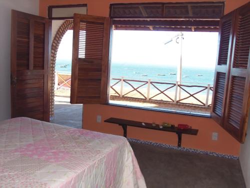 a bedroom with a bed and a view of the ocean at CHALÉ COQUEIROS in Icapuí
