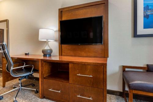 a room with a desk with a television and a chair at Comfort Suites Columbus Airport in Columbus