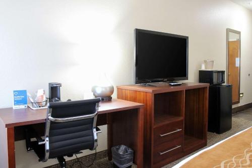 a room with a desk with a television and a chair at Comfort Inn & Suites in Fultondale