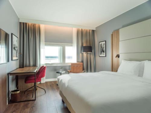 ein Hotelzimmer mit einem großen Bett und einem Schreibtisch in der Unterkunft Radisson Blu Airport Terminal Hotel in Arlanda