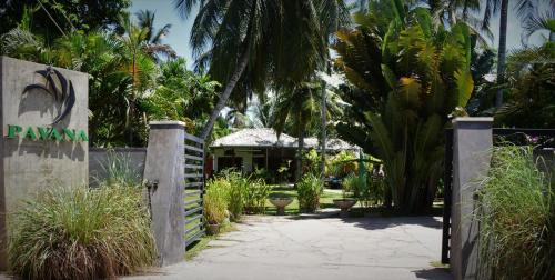 a gate to a garden with palm trees and a house at Pavana Hotel in Negombo