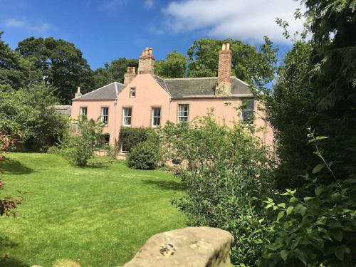an old house with a green yard in front of it at Swinton Manse & Gardens in Swinton