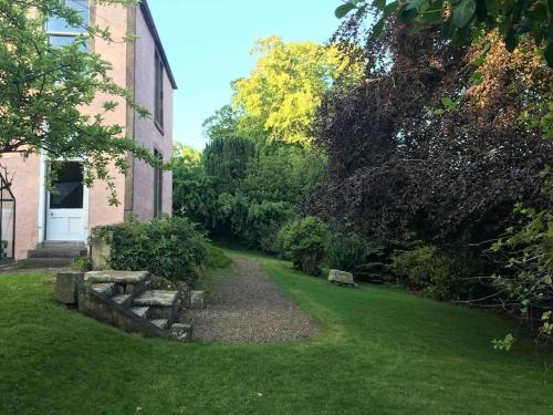 a garden with a stone bench next to a building at Swinton Manse & Gardens in Swinton