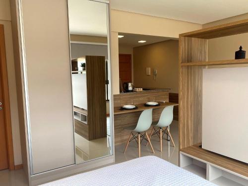 a bedroom with a mirror and two chairs and a kitchen at Loft Belga 2 Master Collection in Passo Fundo