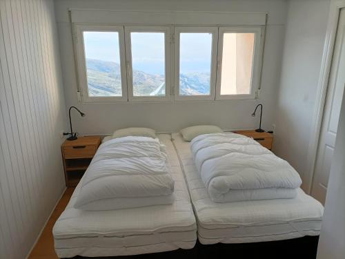 two beds in a room with two windows at Apartamento Sierra Nevada Ski y Ciclismo in Sierra Nevada