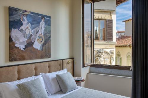 a bedroom with a large window with a painting above a bed at Residenza Mondragone in Florence