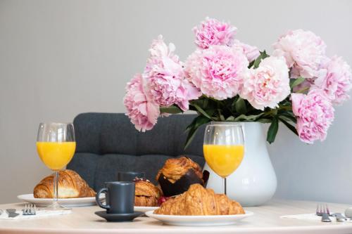 a table with two glasses of orange juice and a vase of pink flowers at Sopot RIVOLI Apartments by Renters in Sopot